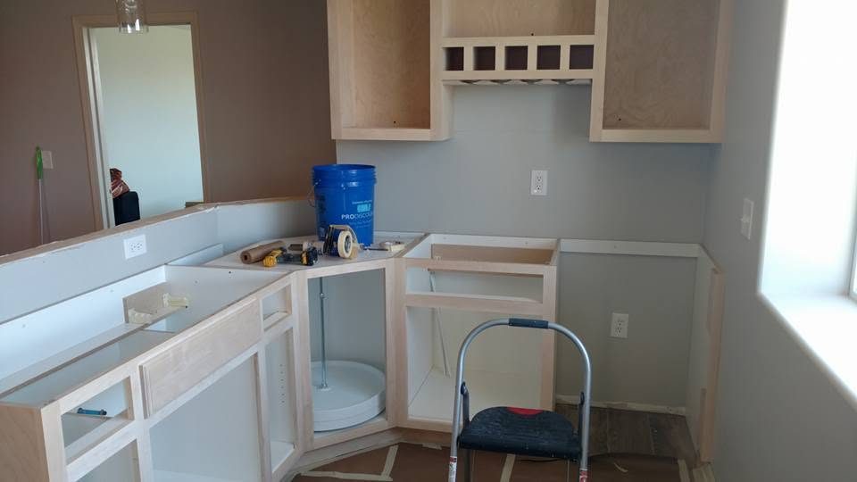 Kitchen renovation in progress with unfinished cabinets, blue bucket, and construction materials