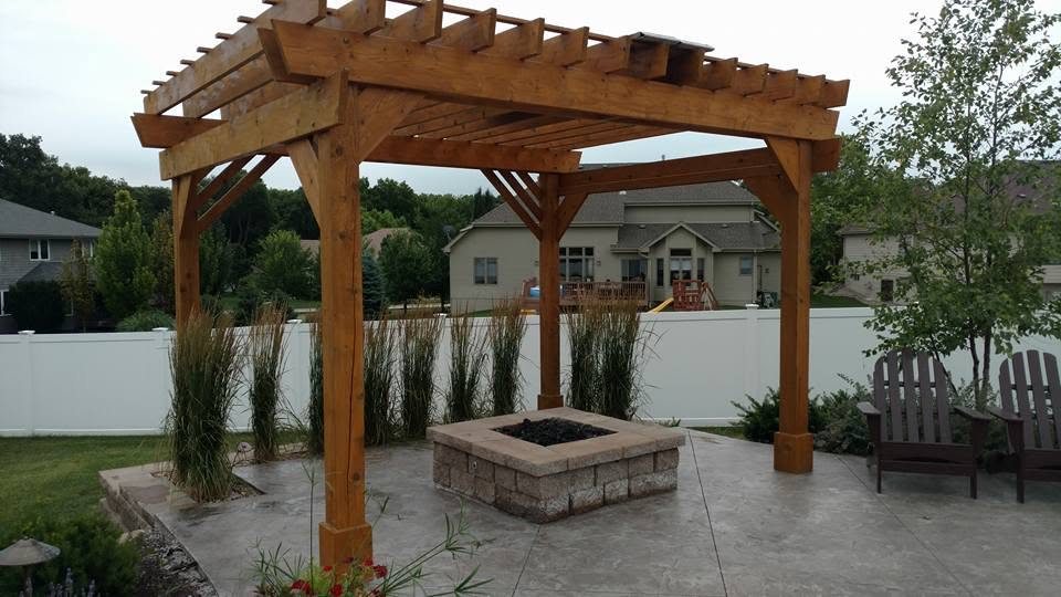 Wooden pergola with fire pit on stamped concrete patio in residential backyard